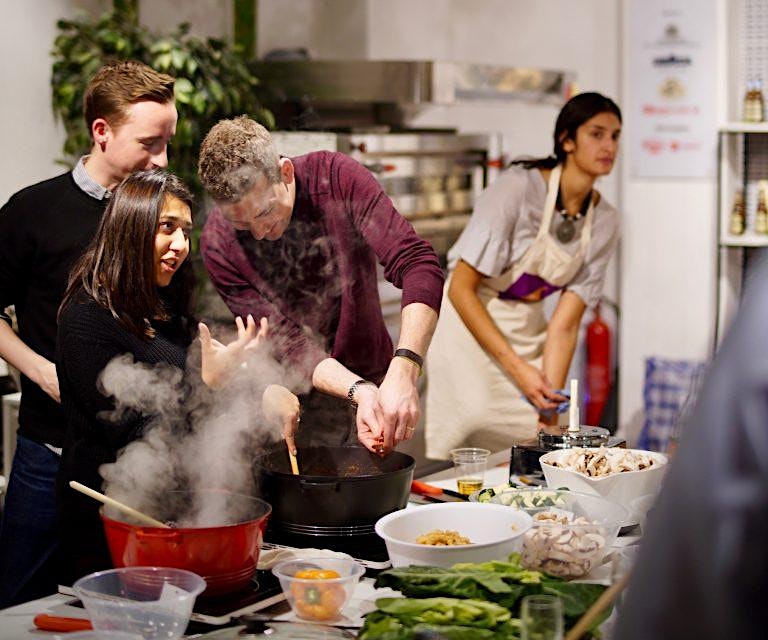Migrateful, a London Cookery Class, brings together a group of people preparing food in a kitchen.
